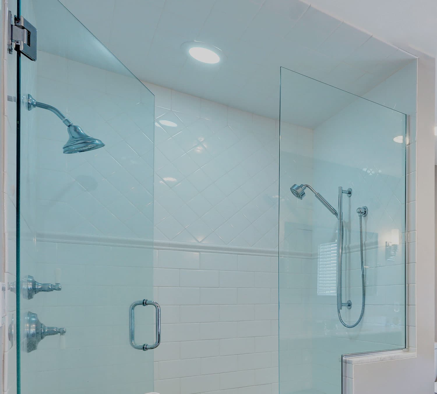 Walk in shower enclosed with frameless glass panels and white subway tiling